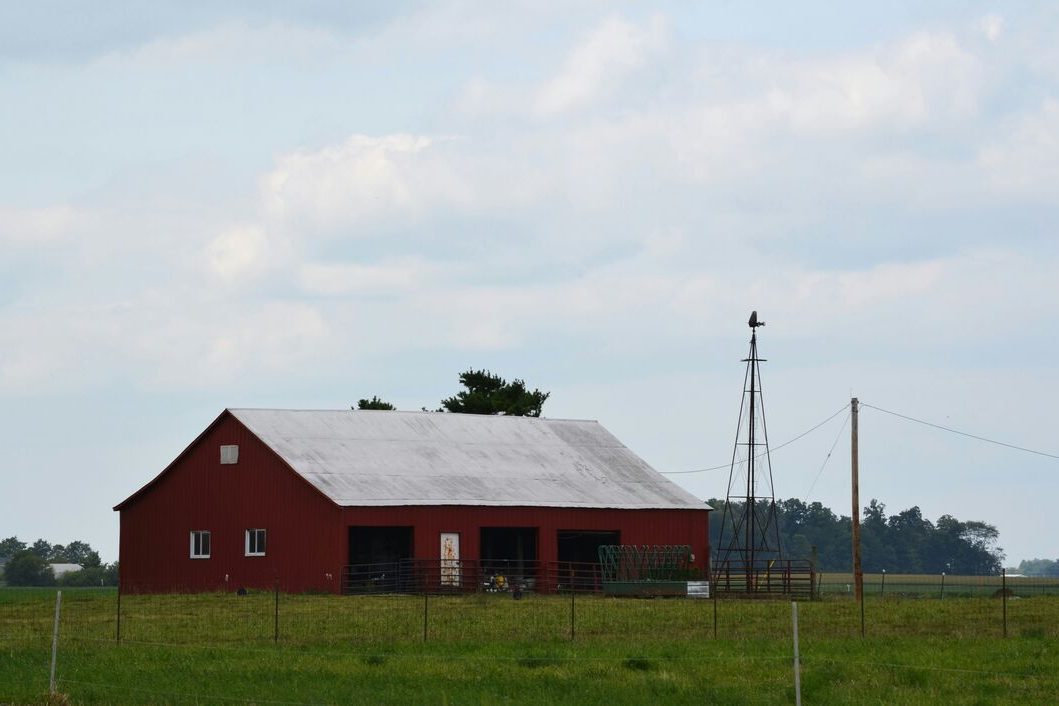 A classic red Vermont barn beside an open growing field.